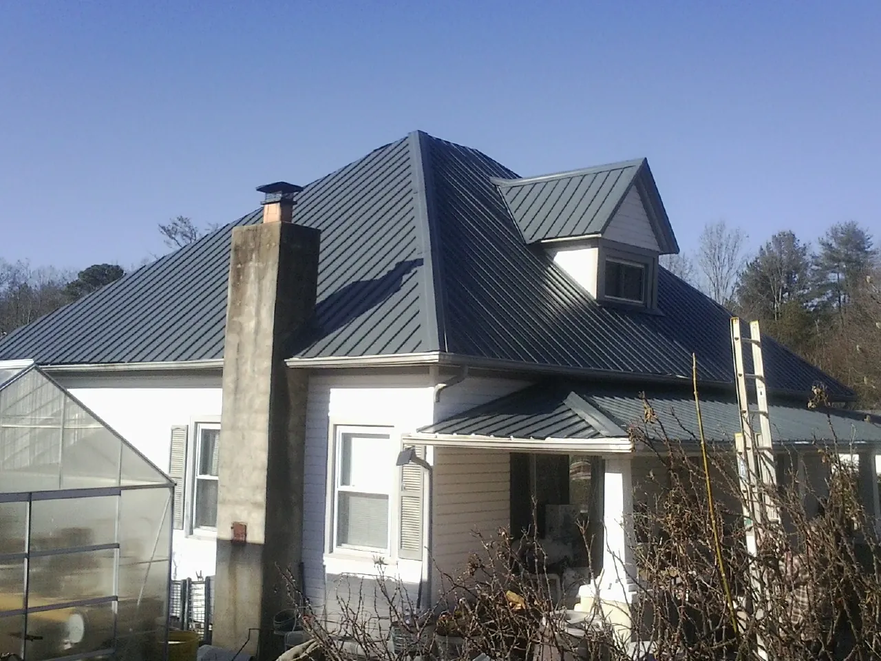 Dark blue standing seam metal roof on a white farmhouse with dormer — Slate & Tile Roof Repair by Roofing Brothers in Maineville