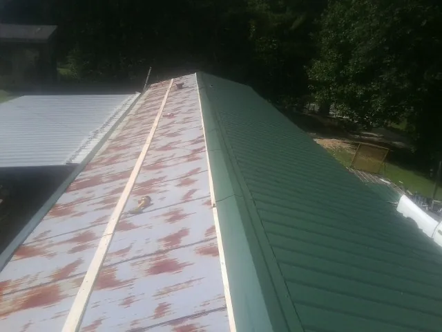 Old rusted panels beside newly installed green metal roofing — Wind Damage Roof Repair by Roofing Brothers in Maineville