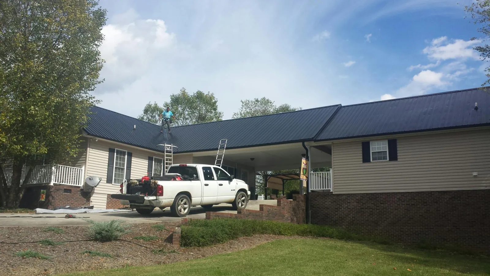 Black metal roof over a home and attached breezeway with ladders set in Maineville