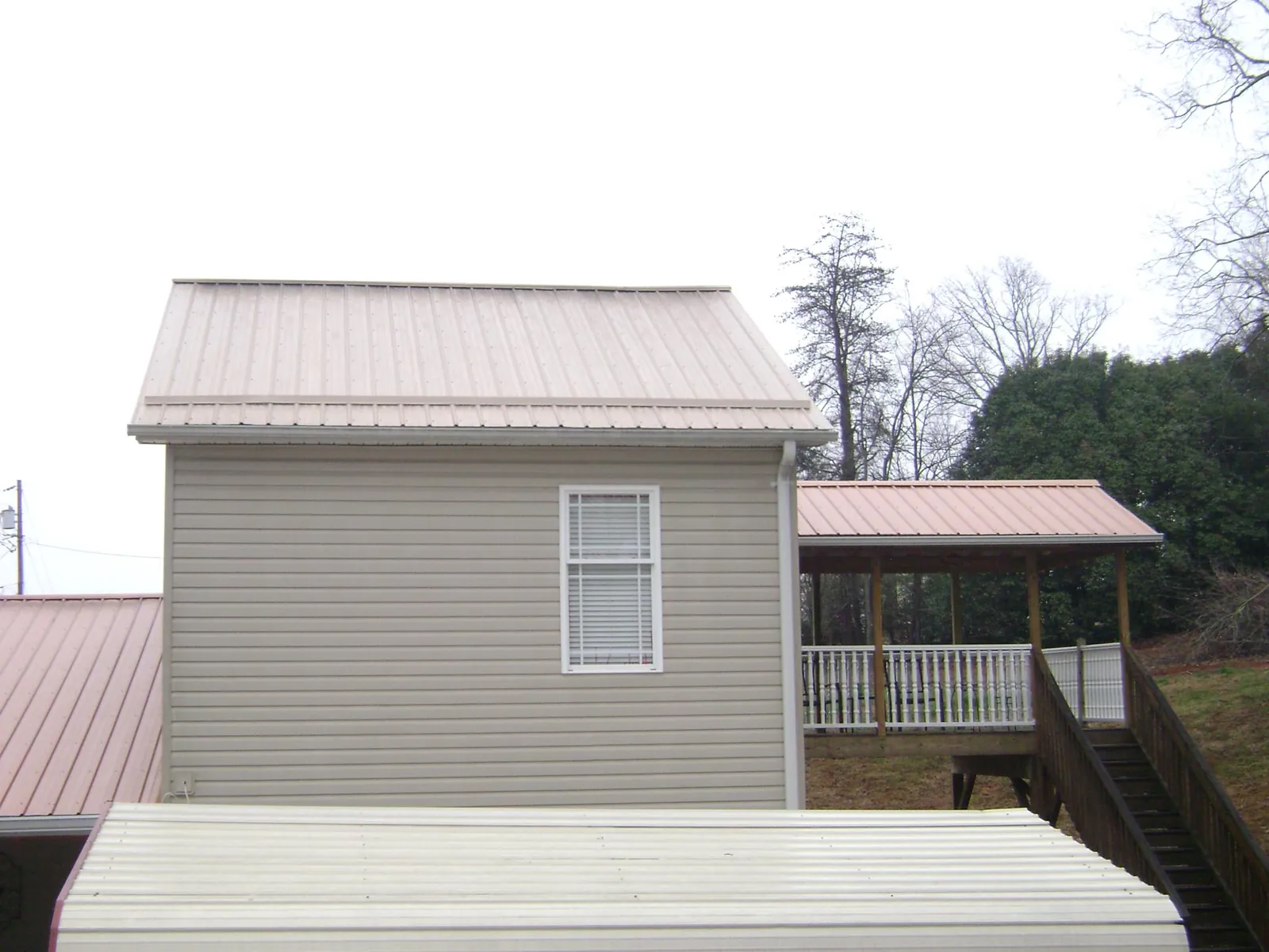 Tan metal roofs on a two story addition and attached porch, from a Roof Replacement job in Maineville