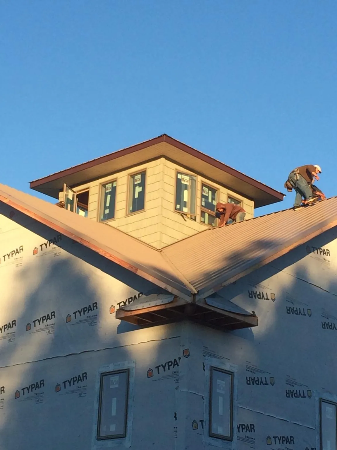Roofers working around a rooftop cupola on a new metal roof at sunset — Roof Waterproofing in Maineville by Roofing Brothers